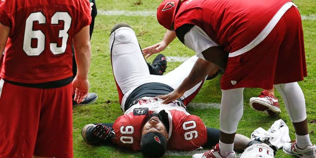 Arizona Cardinals defensive end Darnell Dockett is atended while down in pain during NFL football training camp Monday, Aug. 18, 2014 at University of Phoenix Stadium in Glendale, Ariz. Dockett left the field on a cart. (Photo by Rob Schumacher/The Arizona Republic) (AP Photo/The Arizona Republic, Rob Schumacher) MARICOPA COUNTY OUT; MAGS OUT; NO SALES