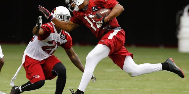 Arizona Cardinals' Michael Floyd, right, makes a catch in front of Tony Jefferson during the first day of NFL football training camp on Saturday, July 26, 2014, in Glendale, Ariz. (AP Photo/Ross D. Franklin)