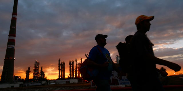 FILE - In this Dec. 20, 2007 file photo, workers leave their shift as Cubans prepare to inaugurate the Camilo Cienfuegos refinery ahead the IV Petrocaribe Summit in Cienfuegos, Cuba. Fears that falling oil prices could knock the wheels off the already wobbly economy of oil-dependent Venezuela have sparked apparent interest in alternatives to Petrocaribe, a trade program created by the late President Hugo Chavez that has kept the region dependent on the South American country for energy. All the countries of the region, except Cuba, are expected to participate in closed talks that will involve U.S. Vice President Joe Biden and other U.S. officials as well as representatives of the European Union, the U.N., and multi-lateral financing agencies such as the World Bank and Inter-American Development Bank. (AP Photo/Dado Galdieri, File)