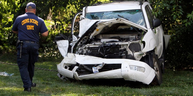 July 25, 2014: An investigator examines a heavily damaged SUV before it is towed from the scene of a fatal accident in North Philadelphia. Two children were killed and three people critically injured when a hijacked car lost control and hit a group of people near a fruit stand, according to police. (AP Photo/ Joseph Kaczmarek)