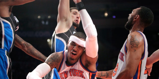 New York Knicks' Carmelo Anthony, center, is knocked down while going for a basket during the first half of an NBA basketball game in New York, Monday, Jan. 16, 2012.  (AP Photo/Seth Wenig)