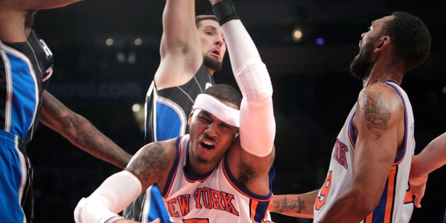 New York Knicks' Carmelo Anthony, center, is knocked down while going for a basket during the first half of an NBA basketball game in New York, Monday, Jan. 16, 2012. (AP Photo/Seth Wenig)