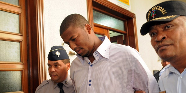 Cleveland Indians pitcher Fausto Carmona, whose real name is Roberto Hernandez Heredia, center, is escorted by police out of court in Santo Domingo, Dominican Republic, Friday Jan. 20, 2012. Hernandez made a tearful apology as he was released on bail following his arrest on Thursday outside the U.S. Consulate in the Dominican capital as he went to get his visa renewed, for allegedly using a false identity to play baseball in the U.S. He is the second Dominican player arrested in recent weeks for using a false identity. (AP Photo/Manuel Diaz)