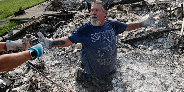 Rick Kincaid reacting as his wife Melodie Kincaid, left, finds his childhood toy as they sift through the charred remains of their home burned in the Carr Fire on Saturday in Redding.