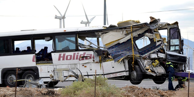 Workers prepare to haul away a tour bus that crashed with semi-truck on Interstate 10 just west of the Indian Canyon Drive off-ramp, in Desert Hot Springs, near Palm Springs, Calif., Sunday, Oct. 23, 2016. The tour bus and a semi-truck crashed on the highway in Southern California early Sunday, killing at least a dozen of people and injuring at least 30 others, some critically, the California Highway Patrol said. (AP Photo/Rodrigo Pena)