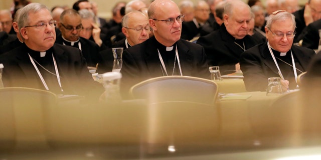 Members of the United States Conference of Catholic Bishops are seen above reflections on a piano as they attend the USCCB's annual fall meeting in Baltimore, Monday, Nov. 14, 2016. The bishops opened their meeting by urging President-elect Donald Trump to adopt humane policies toward immigrants and refugees. (AP Photo/Patrick Semansky)