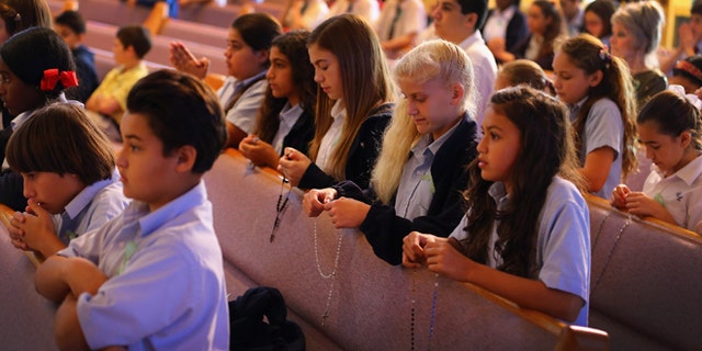Children pray during a service at St. Rose of Lima School on Dec. 21, 2012, in Miami, Florida.