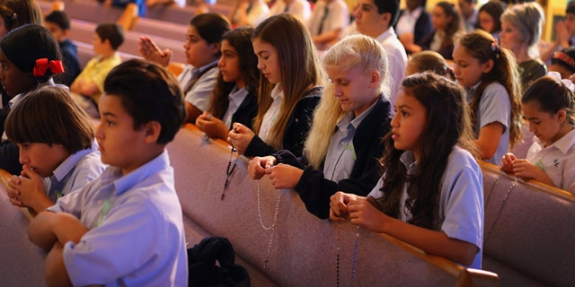 Children pray during a service, at St. Rose of Lima School on December 21, 2012 in Miami, Florida.