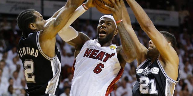 FILE - In this June 10, 2014, file photo, San Antonio Spurs forward Tim Duncan (21) and forward Kawhi Leonard (2) defend against Miami Heat forward LeBron James (6), during the first half in Game 3 of the NBA basketball finals in Miami. They've denied LeBron James winning two NBA titles, and in last year's Finals the Spurs dismantled the Heat, a beatdown that may have hastened the superstar's decision to re-sign with the Cavaliers. On Wednesday, Nov. 19, James faces his nemesis for the first time since June. By(AP Photo/Wilfredo Lee, File)