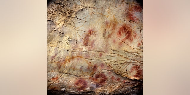 This undated photo shows detail of the Panel of Hands, El Castillo Cave showing red disks and hand stencils made by blowing or spitting paint onto the wall.