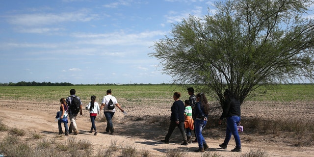 Central American families walk through the countryside after crossing from Mexico on April 14, 2016 in Roma, Texas.
