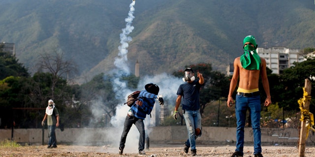A demonstrator throws back a teargas canister towards police lines, during clashes in an anti-government protest in Caracas, Venezuela, Monday, March 10, 2014. The Venezuelan government and opposition appear to have reached a stalemate, in which street protests continue almost daily while the opposition sits out a peace process it calls farcical. (AP Photo/Alejandro Cegarra)