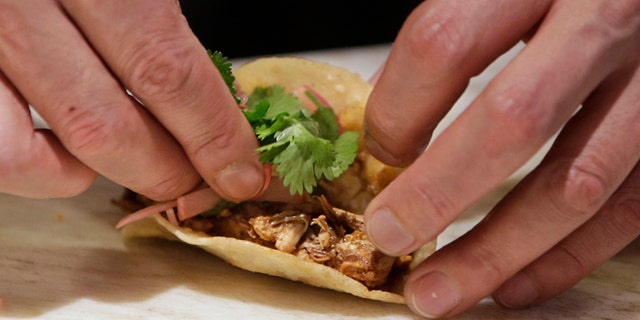 In this photo taken Tuesday, March 11, 2014, line cook Javier Rodriguez uses his bare hands to make chicken tacos at the Hock Farm restaurant in Sacramento, Calif. Under a bill signed last year by Gov. Jerry Brown, chefs and bartenders in California must keep bare hands off food going straight to the plate or the drink glass, and must use gloves or kitchen utensils such as tongs. California, where the law took effect Jan. 1 and will begin enforcement starting in July, will join 41 other states banning bare-hand contact with ready-to-eat food. In February,after receiving a petition from bartenders calling for an exemption for the "disposable glove law" the law's author, Assemblyman Richard Pan, D-Sacramento, a pediatrician, has introduced a bill to repeal the new regulation and revisit the entire issue.(AP Photo/Rich Pedroncelli)