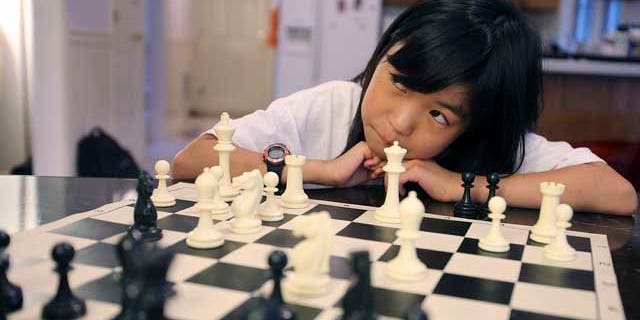 July 9, 2013: Carissa Yip, 9, waits for her father Percy Yip to make a move during a chess match at their home in Chelmsford, Mass.