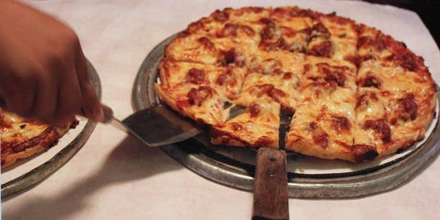Sept. 5, 2014l A waitress serves a cheese and sausage pizza to participants on a pizza tour at Pizano's in Chicago.