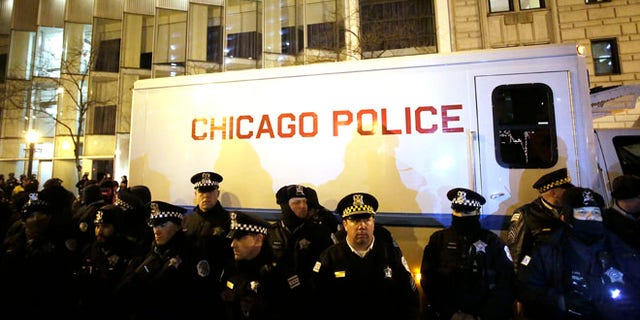 CHICAGO, IL - DECEMBER 18 : Chicago police officers surround a police vehicle as they watch demonstrators protesting the fatal police shooting of Laquan McDonald December 18, 2015 in Chicago, Illinois. Former Chicago police officer Jason Van Dyke, who was charged with murder last month in the shooting death of 17-year-old McDonald last year, was indicted on six counts of first-degree murder and one count of official misconduct earlier this week. (Photo by Joshua Lott/Getty Images)