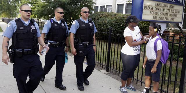 FILE - In this Aug. 26. 2013, file photo, Chicago Police patrol the neighborhood at Gresham Elementary School on the first day of classes in Chicago. Thanks to $1 million from the city, another 100 “Safe Passage” workers will be on routes kids walk through crime-ridden neighborhoods when classes resume Tuesday, Sept. 2, 2014. (AP Photos/M. Spencer Green, File)