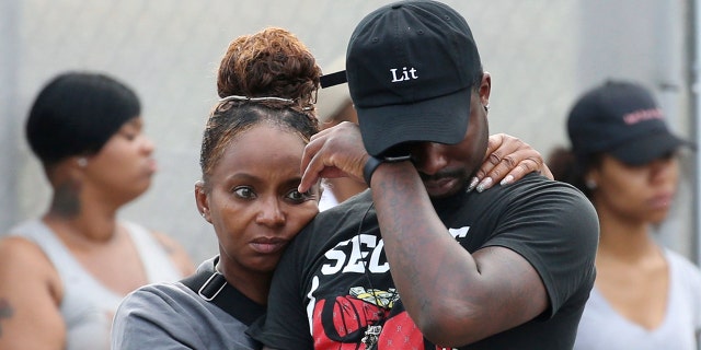 In this Sunday, Aug. 5, 2018 photo, a man wipes his eyes outside the Stroger Hospital in Chicago, after leaving the emergency room due to overwhelming crowds of family and friends of shooting victims.