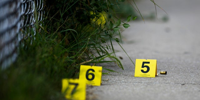 In this Sunday, Aug. 5, 2018 photo, evidence markers sit on the ground at the scene where a boy was killed after being shot in the abdomen while riding his bike in Chicago.