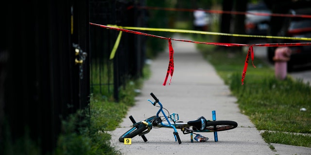 In this Sunday, Aug. 5, 2018 photo, evidence markers sit on the ground at the scene where a boy was killed after being shot in the abdomen while riding his bike in Chicago.
