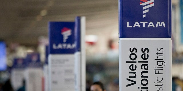 An agent of LATAM airlines stands by the counters at the airport in Santiago, Chile, Monday, July 25, 2016. LATAM airlines created in 2012 after a fusion between the airlines LAN of Chile and TAM of Brazil, has agreed to pay more than $22 million in fines related with a scheme to bribe Argentine union officials via a false consulting contract. The airline will pay the fine to the Securities and Exchange Commission (SEC) and the Department of Justice (DOJ) for a violation of the accounting provisions of the Foreign Corrupt Practices Act. (AP Photo/Esteban Felix)