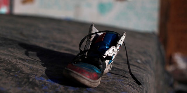 In this Oct. 10, 2016 photo, a discarded shoe lays on top a tarp used by street children for shelter in a ruined building in Santiago, Chile. Many if not all of the youths living in the ruin were once wards of the state, living in shelters of National Service for Minors. (AP Photo/Luis Hidalgo)