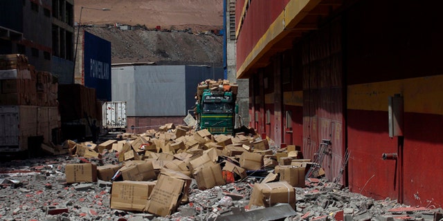 A truck remains covered by debris and boxes of fallen merchandise that fell from the earthquake ravaged Duty Free Zone of Iquique, in Iquique, Chile, Friday, April 4, 2014. Following a magnitude-8.2 earthquake early in the week, soldiers have kept a close watch on supermarkets and gas stations to prevent looting as many people continued to line up on Friday for gasoline, water and food. The city remained largely peaceful and no new major damage or casualties were reported from the continuing aftershocks that have rattled the sleep-deprived citizens of Chile's north. (AP Photo/Luis Hidalgo)