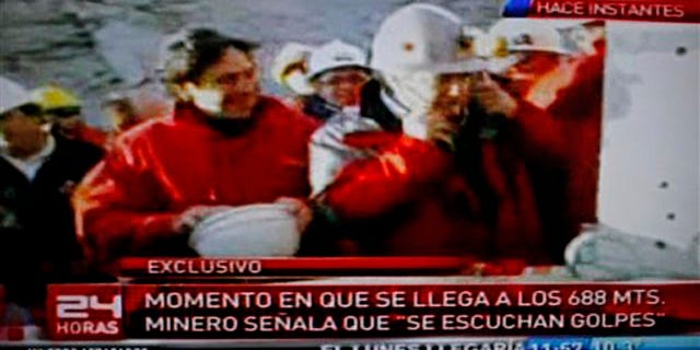 Aug. 22: Chile's Mining Minister Laurence Golborne, left, smiles as an unidentified official listens with a medical oscilloscope to unknown sounds coming from the area of a collapsed mine where about 33 miners have been trapped for 17 days in Copiapo, Chile, on Sunday.