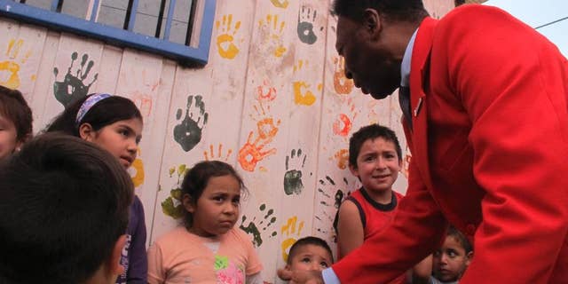 Brazilian soccer legend Pele puts out his hand, while greeting children in a visit to a slum in Santiago, Chile, Thursday, April 9, 2015. The activity was organized Thursday by a local NGO and a bank, seeking to inspire Chilean children. Pele says he has "happily recovered" from a recent health scare. (AP Photo/Luis Andres Henao)