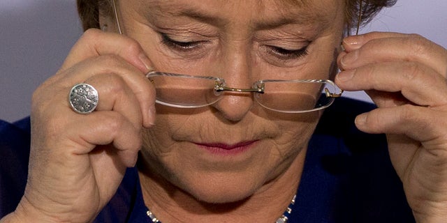 FILE - In this Dec. 9, 2014, file photo, Chile's President Michelle Bachelet puts on her glasses during an event to announce a new economic report on Latin America at the 2014 Iberoamerican Summit in Veracruz, Mexico. President Bachelet came under fire on Wednesday Feb. 11, 2015, over complaints her family got privileged access to a bank loan for a land deal. Chileâs Que Pasa magazine reported that a company half-owned by Bacheletâs daughter-in-law, Natalia Compagnon, received a $10 million loan from Banco de Chile. (AP Photo/Rebecca Blackwell, File)