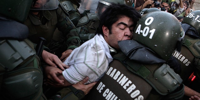Police officers detain a human rights activist after clashes during an event honoring Miguel Krassnoff, a former Chilean army brigadier during the 1973-1990 dictatorship of August Pinochet, in Santiago, Chile, Monday, Nov. 21, 2011. Krassnoff is currently serving a 144-year sentence for homicide and forced disappearances. (AP Photo/Luis Hidalgo)