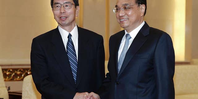 FILE - In this March 23, 2015 file photo, Asian Development Bank President Takehiko Nakao, left, poses with Chinese Premier Li Keqiang for a photo at the Great Hall of the People in Beijing. The president of the Asian Development Bank says a proposed Chinese-led regional bank is a potential partner instead of a rival and the ADB is talking with Beijing to share its experience. (AP Photo/Lintao Zhang, Pool, File)