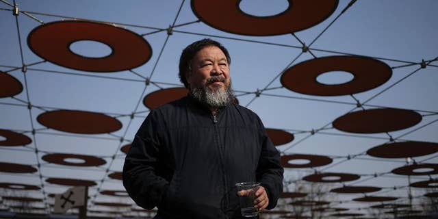 FILE - In this March 24, 2015 file photo, Chinese dissident artist Ai Weiwei walks near a playground outside a shopping mall in Beijing. Ai has his passport back four years after it was confiscated by authorities. Ai on Wednesday, July 22, 2015, posted a photo of himself on Instagram holding a Chinese passport with the caption, “Today, I got my passport.” (AP Photo/Andy Wong, File)