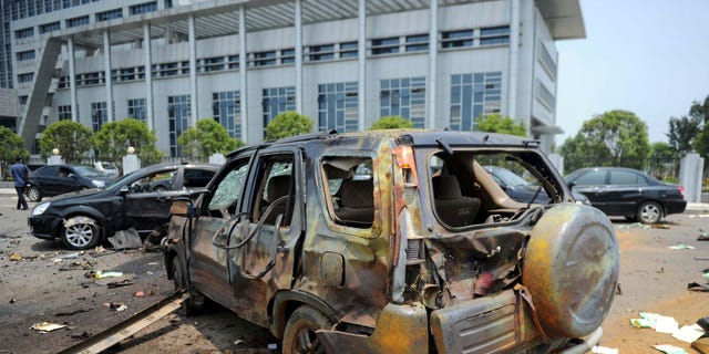 A damaged vehicle sits at the site of an explosion near the Linchuan district government building in Fuzhou city, east China's Jiangxi Province. Hours after homemade bombs blasted government buildings, some Chinese were quick to glorify the disgruntled bomb-setter _ a sign of the bitterness many feel toward the government for chasing growth while neglecting justice.