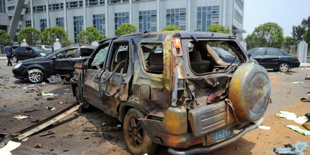A damaged vehicle sits at the site of an explosion near the Linchuan district government building in Fuzhou city, east China's Jiangxi Province. Hours after homemade bombs blasted government buildings, some Chinese were quick to glorify the disgruntled bomb-setter _ a sign of the bitterness many feel toward the government for chasing growth while neglecting justice.