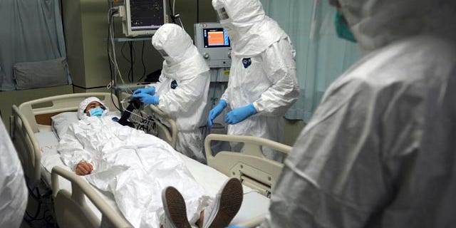 October 23, 2014: Medical workers wearing protective suits treat a mock patient during a training exercise on dealing with a suspected Ebola case at a hospital in Guangzhou in south China's Guangdong province. (AP Photo)