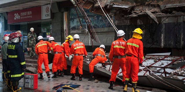 July 18, 2014: Rescuers try to remove a steel frame from a collapsed concrete roof which killed and injured a number of people after they took shelter during heavy rains in Shenzhen in south China's Guangdong province. (AP Photo)