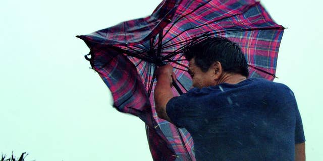 In this Aug. 8, 2015 photo provided by China's Xinhua News Agency, a man walks against gale in Shishi, southeast China's Fujian Province. Typhoon Soudelor hit the city of Putian in Fujian province late Saturday night and weakened into a tropical storm as it moved across the province. The Fujian Civil Affairs Department said that it collapsed 36 houses and damaged 281 others. (Zhang Guojun/Xinhua News Agency via AP) NO SALES
