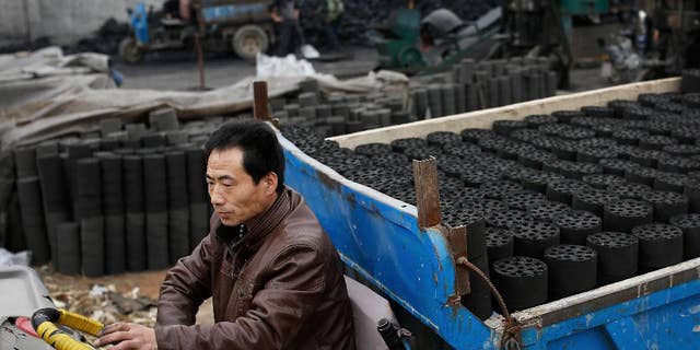In this Nov. 27, 2014 photo, a man drives his tricycle cart loaded with coal briquettes as he leaves a coal process station in Tangxian in China's Hebei province. Coal production in China, the world's biggest coal-consuming nation, fell by 6 percent in the first four months of the year 2015 as the economy slows and the government makes a concerted push to reduce carbon emissions. The National Development and Reform Commission said Tuesday, May 26, 2015 that Chinese imports of coal also fell, plummeting 38 percent. (AP Photo/Andy Wong)
