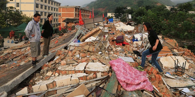 August 5, 2014: In this photo provided by China's Xinhua News Agency, teachers search for their belongings from collapsed dormitories at Longquan Middle School in Longtoushan town of Ludian county, southwest China's Yunnan Province. (AP Photo/Xinhua, Xing Guangli)