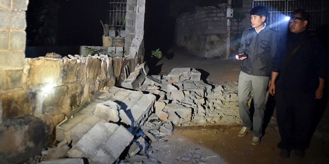October 8, 2014: In this photo released by China's Xinhua News Agency, villagers check a damaged house at Mangla Village of Yongping Township at Jinggu County of Pu'er City, southwest China's Yunnan Province. (AP Photo/Xinhua, Chen Haining)