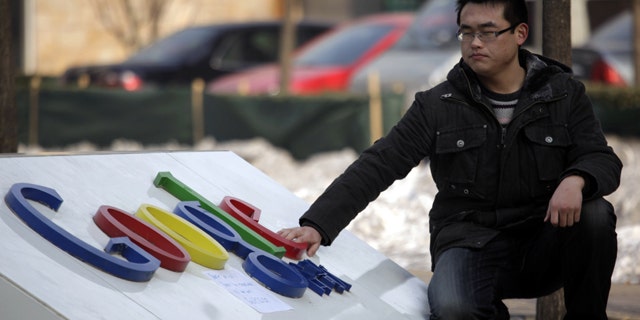 A Chinese man shuts his eyes briefly as he places a hand on the Google logo outside the Google China headquarters in Beijing.