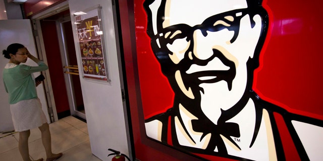 FILE - In this July 31, 2014 photo, a woman looks at a menu with words 'everyday half-price' in front of a KFC fast food restaurant in Beijing, China. (AP Photo/Andy Wong, File)