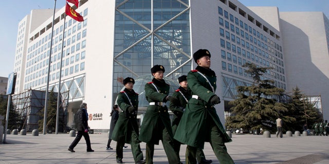 In this Thursday, Feb. 25, 2016, photo, Chinese paramilitary policemen march outside the Bank of China headquarters in Beijing, China. Convicted con man Gilbert Chikli is credited with masterminding a fraud that has cost major multinational companies $1.8 billion in just over two years. Chikli said he laundered 90 percent of his money through China and Hong Kong. Police traced tens of thousands in transfers from Chikli front companies to Bank of China accounts. (AP Photo/Ng Han Guan)