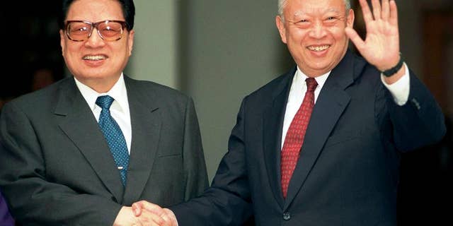 FILE - In this Feb.11, 1998 file photo, then Hong Kong leader Tung Chee-hwa, right, waves to photographers while shaking hands with then China's legislative leader Qiao Shi outside Government House in Hong Kong. Qiao Shi, a senior Communist Party official and chairman of China's legislature in the 1990s, died Sunday, June 14, 2015 at the age of 91, state media said. (AP Photo/Anat Givon, File)