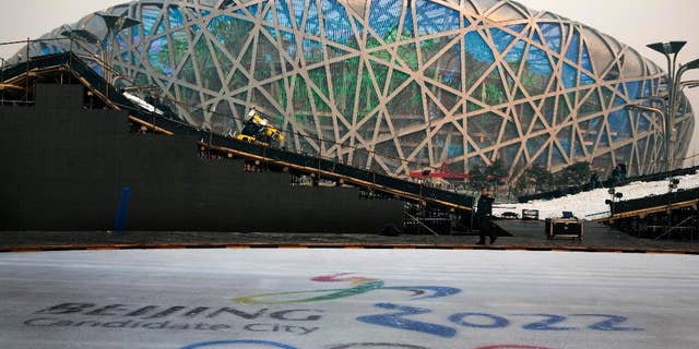 FOR STORY OLYMPICS 2022 BID - FILE - In this Dec. 26, 2014 file photo, a worker walks past an ice rink with the logo for Beijing's Winter Olympics bid ahead of a countdown event to the new year in front of the iconic Beijing National Stadium "Bird's Nest" in Beijing. The International Olympic Committee will be faced with two starkly different choices, Beijing and Almaty, Kazakhstan , when it selects the host city for the 2022 Winter Games, on July 31 in Kuala Lumpur, Malaysia. (AP Photo/Ng Han Guan, File)