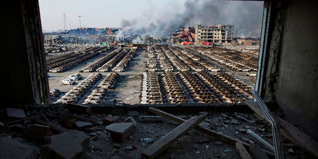 FILE - In this Aug. 13, 2015 photo, a shattered window frames the site of an explosion at a port warehouse in northeastern China's Tianjin municipality. (AP Photo/Ng Han Guan. File)