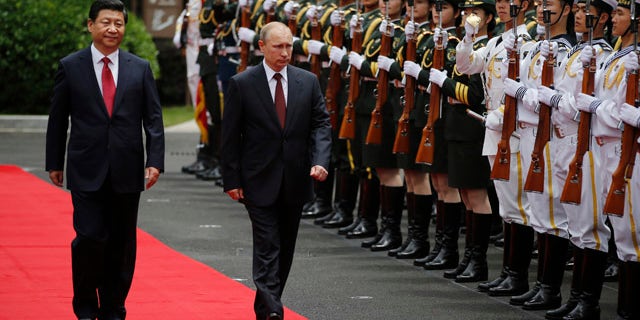 May 20, 2014: Russia's President Vladimir Putin, center, and China's President Xi Jinping, left, review an honor guard during a welcoming ceremony at the Xijiao State Guesthouse ahead of the fourth Conference on Interaction and Confidence Building Measures in Asia (CICA) summit in Shanghai. (AP Photo/Carlos Barria, Pool)