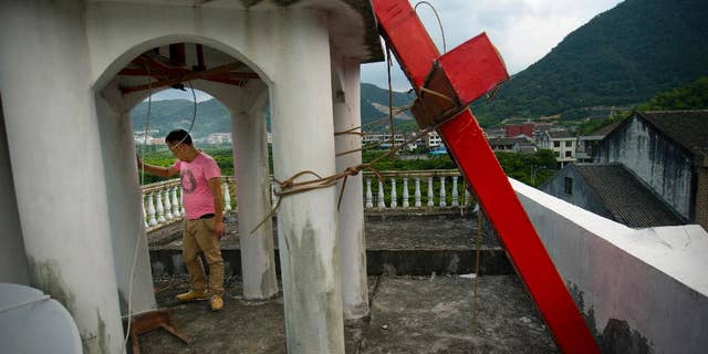 Lay leader Tu Shouzhe stands on his Protestant church's roof hours after Chinese government workers came and cut down the building's cross.