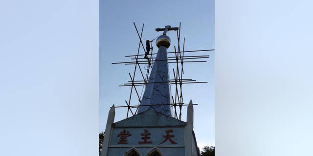 A cross atop the Lower Dafei Catholic Church topples after being cut down by a Chinese government worker with a cutting torch.